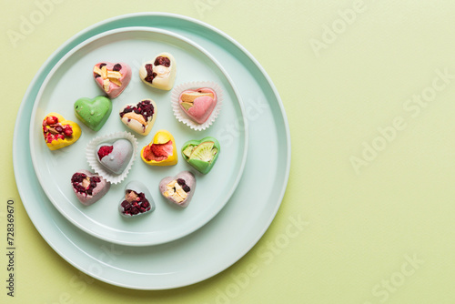 Plate with different chocolate on colored background. Assortment of fine chocolates top view vith copy space Health and obesity concept