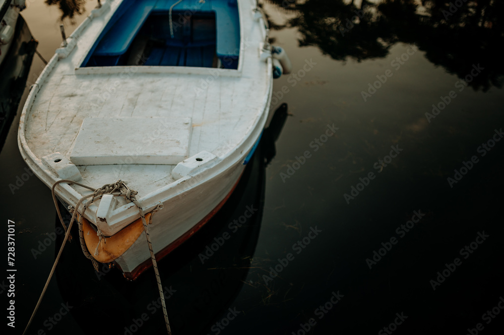 Small boat on calm water, moored in the harbor during sunset. Small boat on calm water, moored in the harbor during sunset.