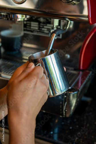 Boilink milk in a coffee machine for preparing cappuccino in a coffee shop - stock photo