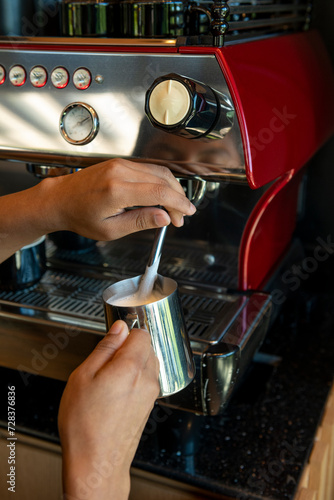 Boilink milk in a coffee machine for preparing cappuccino in a coffee shop - stock photo