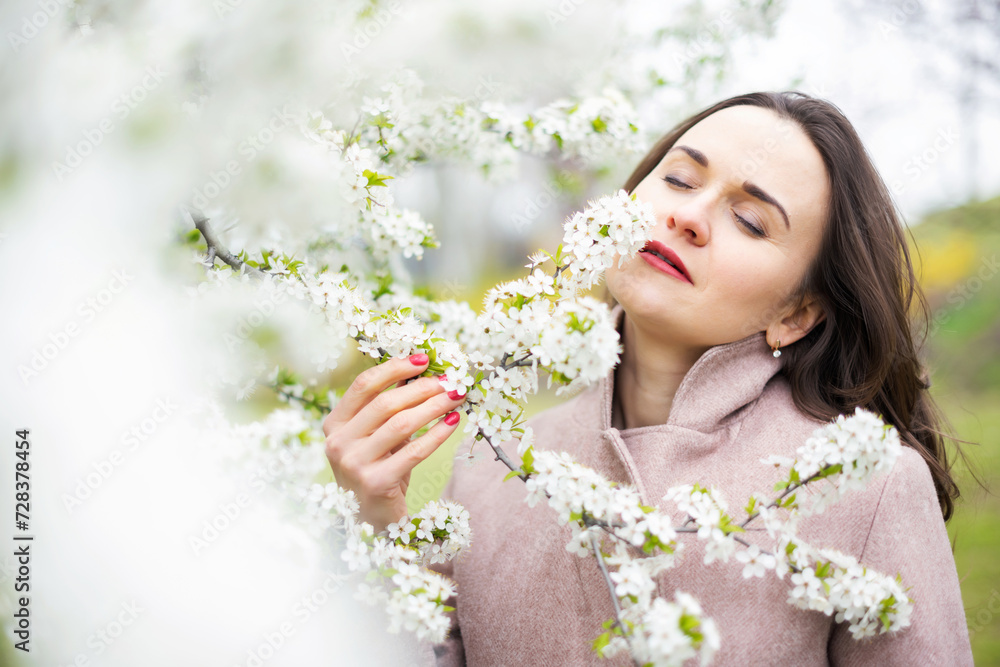 Healthy happy woman on spring outdoors. Smiling young woman on the spring garden enjoy blooming flowers of tree. Enjoy Nature. No allergy.