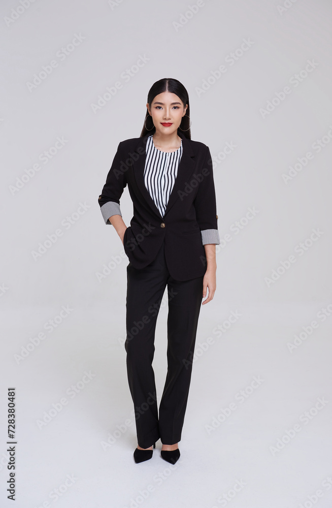 Full length portrait of an attractive smart asian businesswoman in suit standing with looking at camera isolated on gray background. Full length portrait of an attractive smart asian businesswoman in suit standing with looking at camera isolated on gray background.