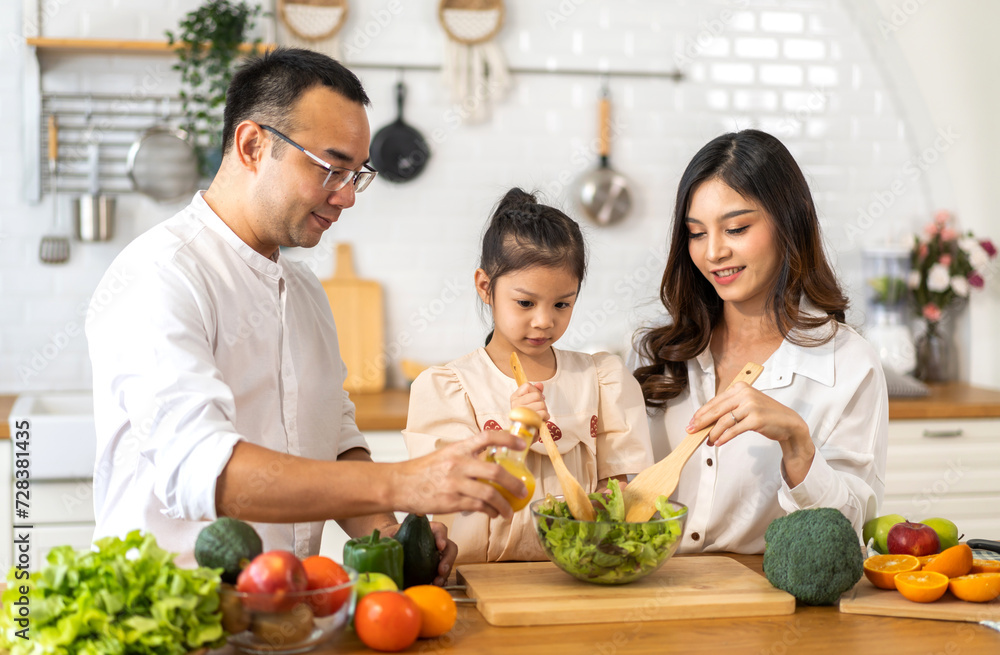 Portrait of enjoy happy love asian family father and mother with little asian girl daughter child having fun help cooking food healthy eat together with fresh vegetable salad ingredient in kitchen