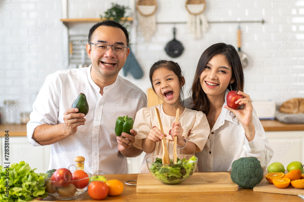 Portrait of enjoy happy love asian family father and mother with little asian girl daughter child having fun help cooking food healthy eat together with fresh vegetable salad ingredient in kitchen Portrait of enjoy happy love asian family father and mother with little asian girl daughter child having fun help cooking food healthy eat together with fresh vegetable salad ingredient in kitchen