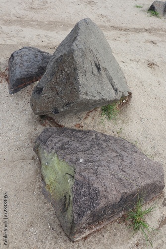 Several large Rocks lie on the sand beach.