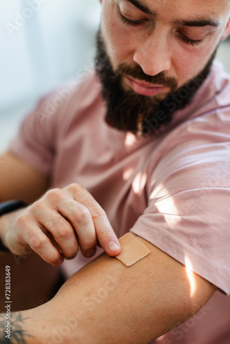 Slika na platnu Young man putting nicotine patch on his shoulder, New Year's resolutions, quitting smoking, healthy lifestyle without cigarettes