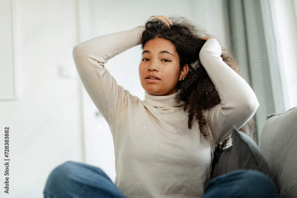 Portrait of beautiful curvy woman, sitting on bed, holding her hair, looking at camera. Portrait of beautiful curvy woman, sitting on bed, holding her hair, looking at camera.