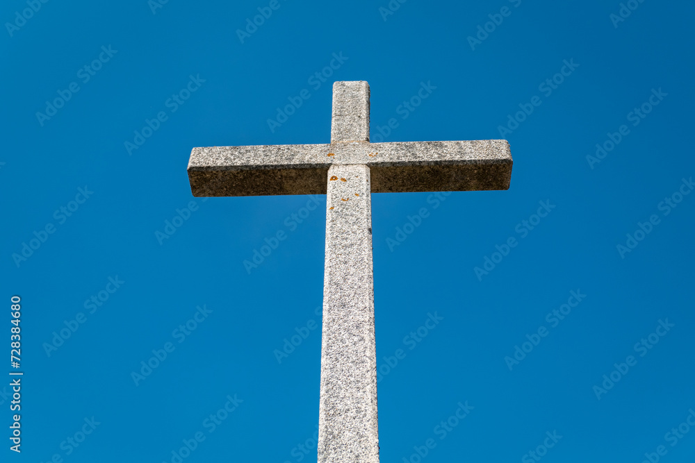Escultura celestial: Uma cruz de granito erguida sob o manto azul do céu