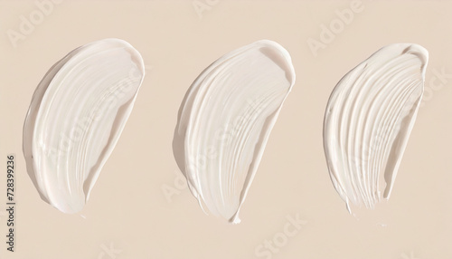 Smears of liquid foundation isolated on beige background. Different skin tone bb cream swatches photo