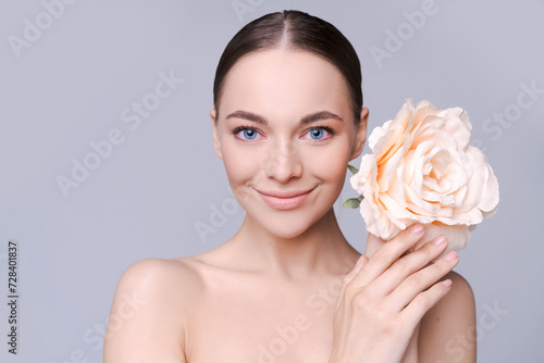 Portrait beautiful young woman with clean fresh skin. Model with healthy skin  close up portrait. Cosmetology  beauty and spa. Girl with a pink flower