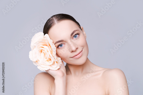 Portrait beautiful young woman with clean fresh skin. Model with healthy skin  close up portrait. Cosmetology  beauty and spa. Girl with a pink flower