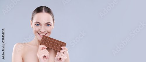 Close up beautiful girl biting chocolate bar joyfully on white background  studio shot
