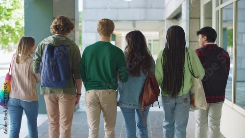 back view of a multi-ethnic group of students in language exchange program walking together outside college