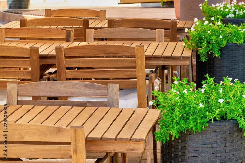 wooden furniture, tables and chairs of a cozy outdoor cafe on a clear sunny summer day. beautiful postcard for the designer. desktop background