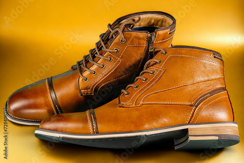 A pair of premium calfskin boots on a yellow background. Horizontal shot.