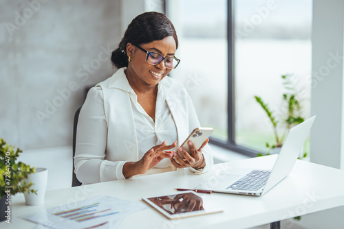 Business girl with phone typing during work break replying to email, sms message or networking via social media app. Communication, text conversation and black woman using smartphone for web search photo