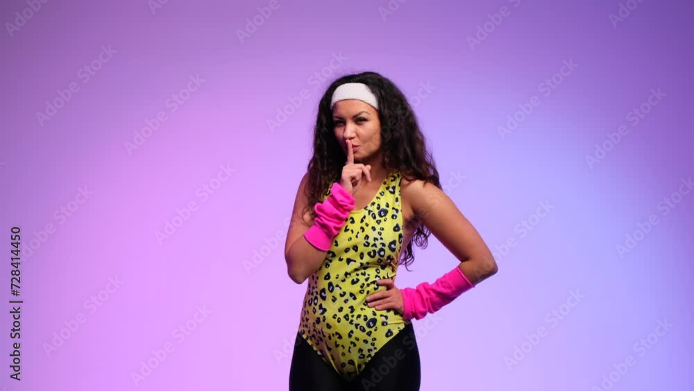 Happy retro woman playfully shows shhh gesture and winks her eye on purple background. Showing the importance of keeping a secret, gossip, privacy, confidential. Happy retro woman playfully shows shhh gesture and winks her eye on purple background. Showing the importance of keeping a secret, gossip, privacy, confidential.