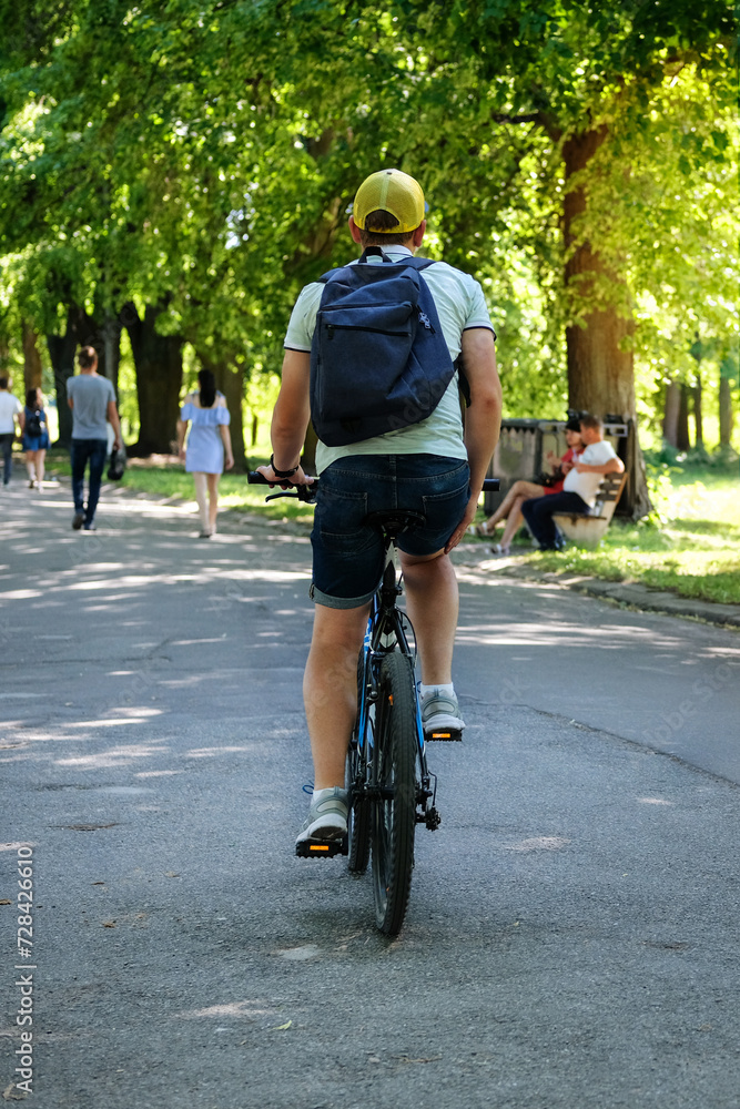 Fototapeta premium Cyclist spend their time on bicycle in park on sunny day. Ride for exercise and relaxation. Healthy lifestyle. Sport and active life concept.