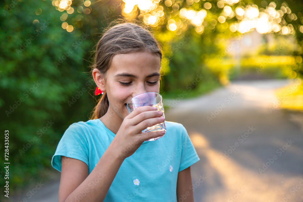 A child drinks water from a glass. Selective focus.