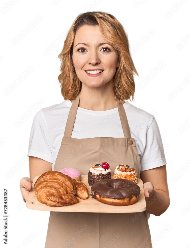 Caucasian middle-aged female baker with sweets tray in studio Caucasian middle-aged female baker with sweets tray in studio