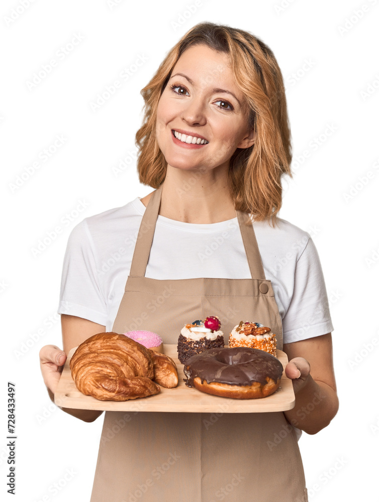 Caucasian middle-aged female baker with sweets tray in studio Caucasian middle-aged female baker with sweets tray in studio