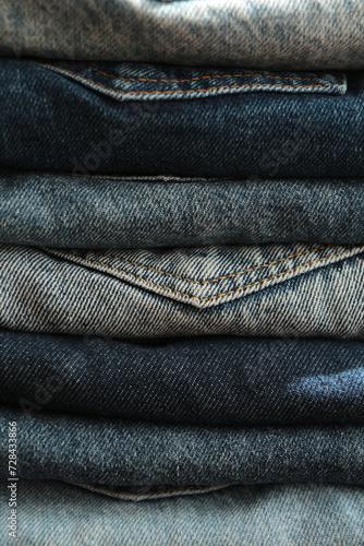  Close up the Stack of jeans in different shades of blue. Folded denim jeans pants, different shades of denim jeans in a row. Denim texture or denim jeans background.