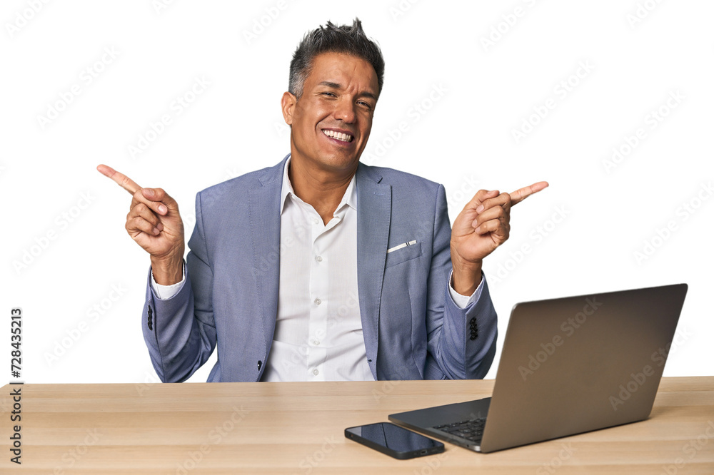 Elegant businessman at desk with laptop pointing to different copy spaces, choosing one of them, showing with finger. Elegant businessman at desk with laptop pointing to different copy spaces, choosing one of them, showing with finger.