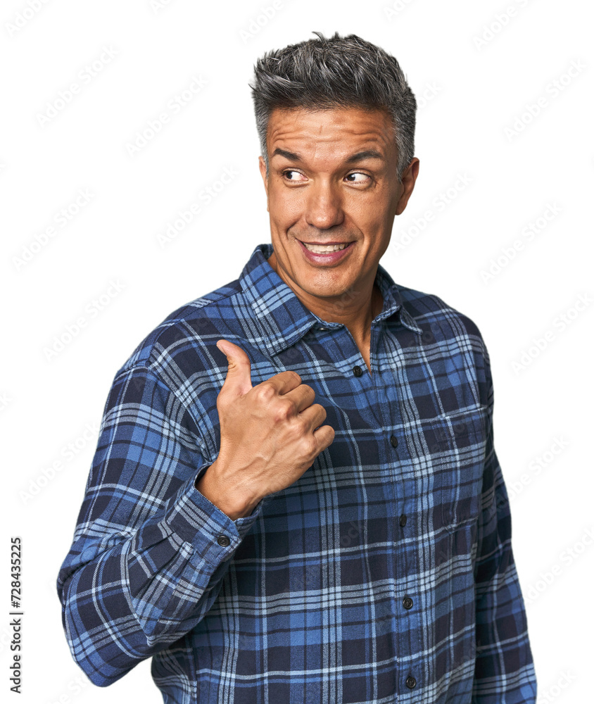 Middle-aged Latino man points with thumb finger away, laughing and carefree. Middle-aged Latino man points with thumb finger away, laughing and carefree.
