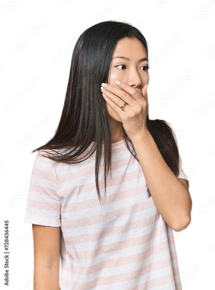 Young Chinese woman in studio setting thoughtful looking to a copy space covering mouth with hand. Young Chinese woman in studio setting thoughtful looking to a copy space covering mouth with hand.