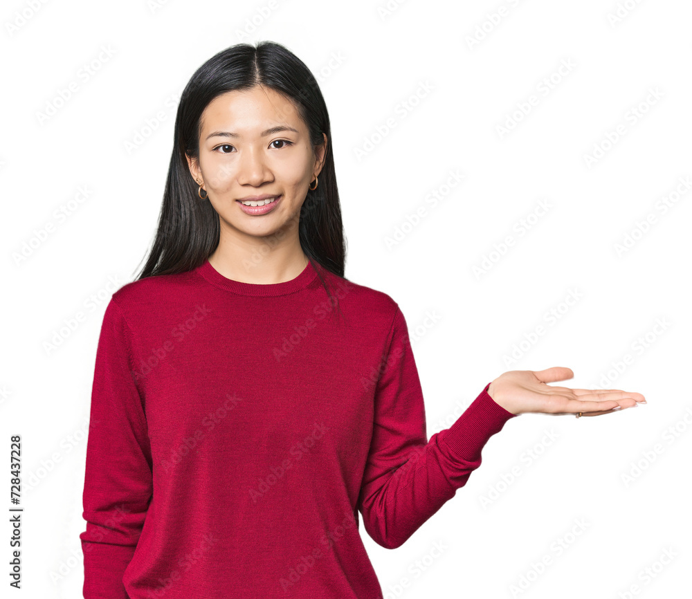 Young Chinese woman in studio setting showing a copy space on a palm and holding another hand on waist. Young Chinese woman in studio setting showing a copy space on a palm and holding another hand on waist.