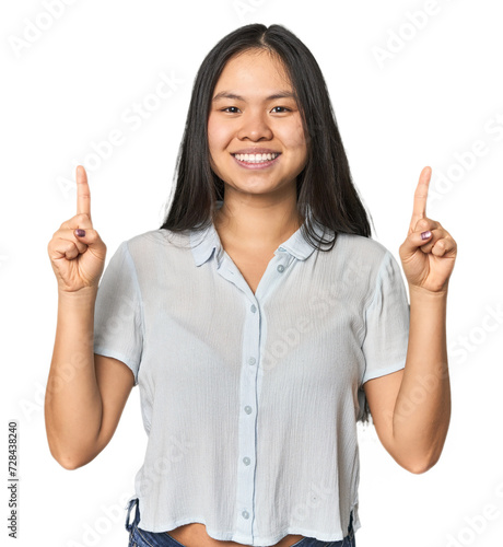 Young chinese woman isolated indicates with both fore fingers up showing a blank space.