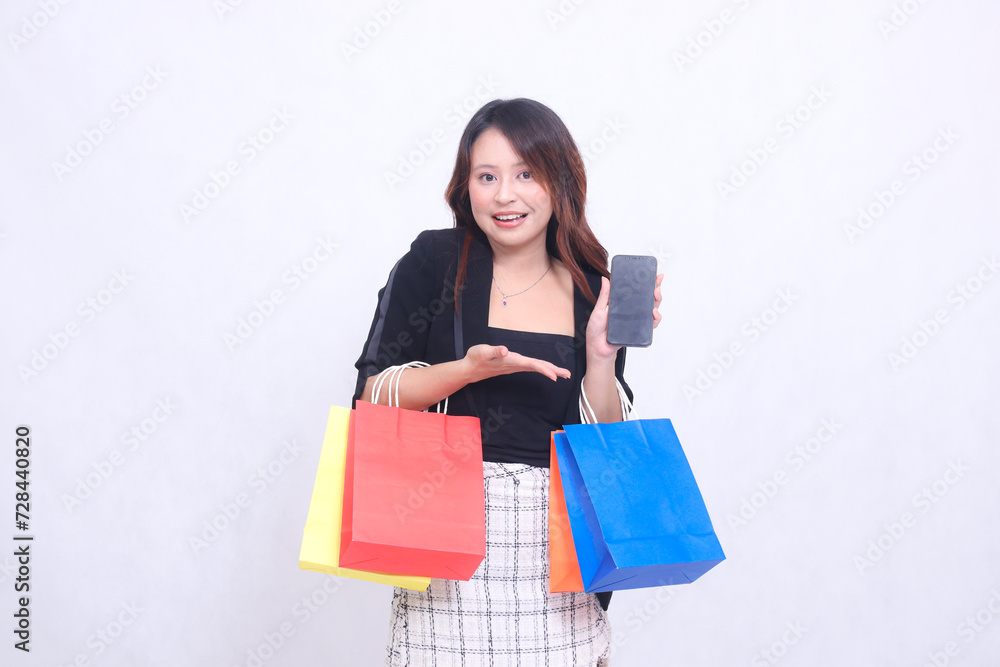 customer beautiful asian girl 20s formal office smile introduces cell phone gadget while carrying shopping paper bag isolated white background customer beautiful asian girl 20s formal office smile introduces cell phone gadget while carrying shopping paper bag isolated white background