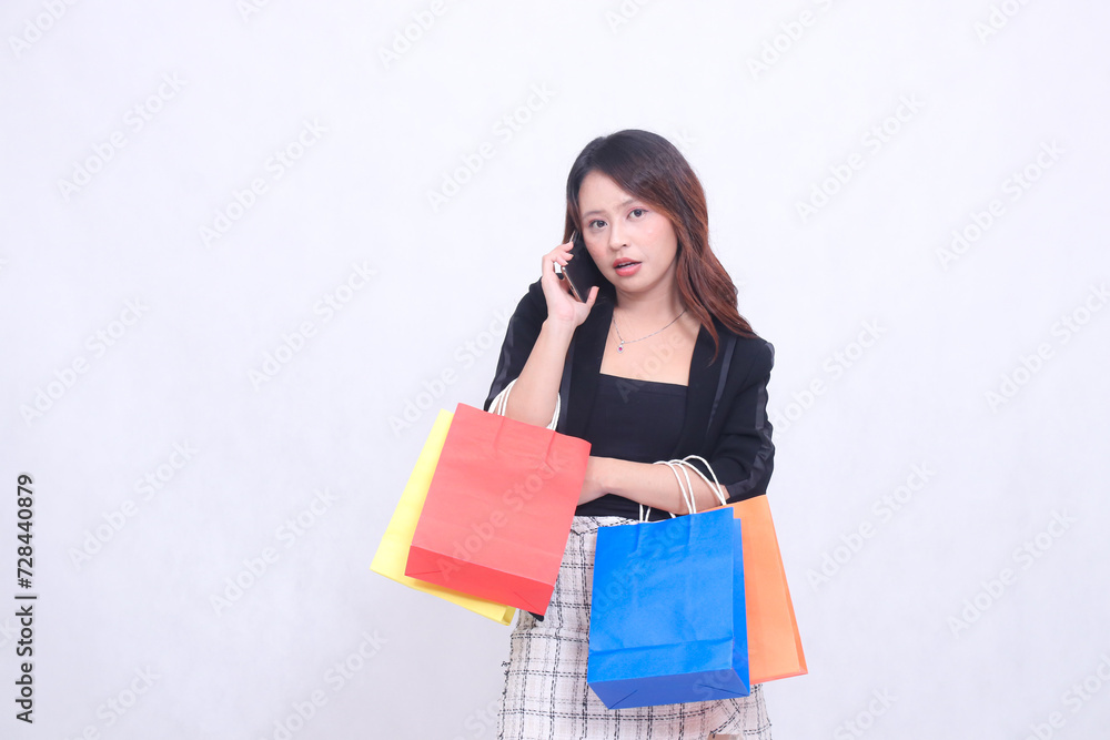 Beautiful Asian girl 20s formal office customer surprised relaxed on the phone looking at the camera while carrying a shopping paper bag isolated on a white background Beautiful Asian girl 20s formal office customer surprised relaxed on the phone looking at the camera while carrying a shopping paper bag isolated on a white background