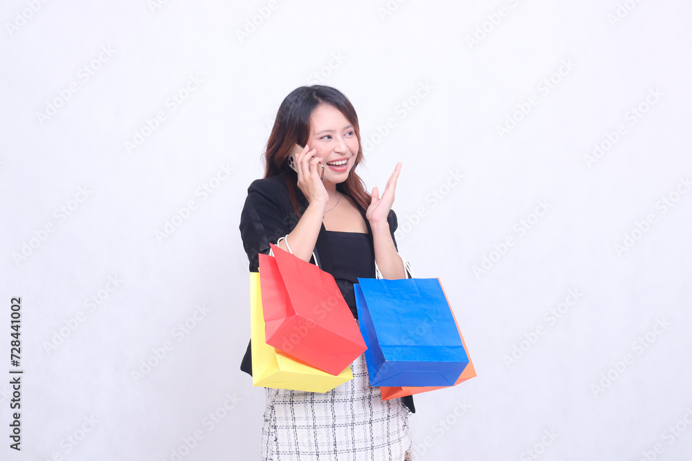 beautiful asian woman customer 20s formal office smiling laughing while on the phone hand to the side top left while carrying shopping paper bag isolated white background beautiful asian woman customer 20s formal office smiling laughing while on the phone hand to the side top left while carrying shopping paper bag isolated white background