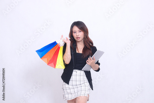 Young beautiful woman customer 20s formal office flat smile holding tablet pen and carrying shopping paper bag aside isolated white background