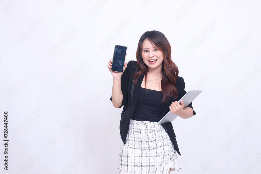 beautiful Indonesian girl 20s formal office happy looking at black cellphone gadget slightly tilted and carrying tablet for promo isolated white background