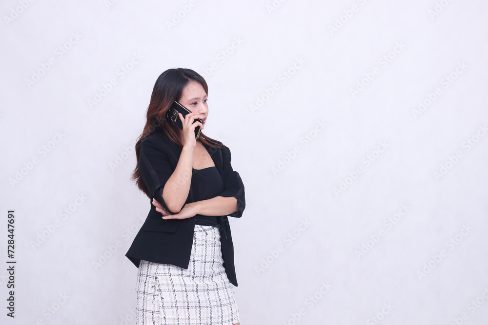 the charm of a beautiful Asian office woman in her 20s flat expression is on the phone using a cellphone gadget for promos while holding her arms to the left isolated on a white background the charm of a beautiful Asian office woman in her 20s flat expression is on the phone using a cellphone gadget for promos while holding her arms to the left isolated on a white background