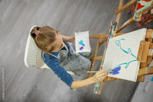 Concentrated Child Painting on Easel. Top view. photo