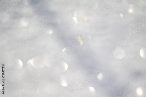 Blurred white bokeh background, snow sparkles in the sun