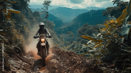 A motorcyclist rides on a muddy trail through dense tropical jungle.