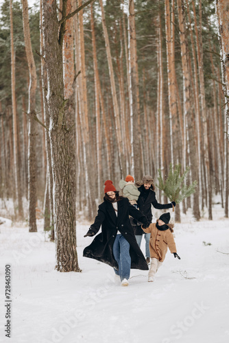 Happy loving family  Father  mother and children are playing and hugging outdoors. Cute little kids and parents on snowy winter walk in nature. Frost winter season concept