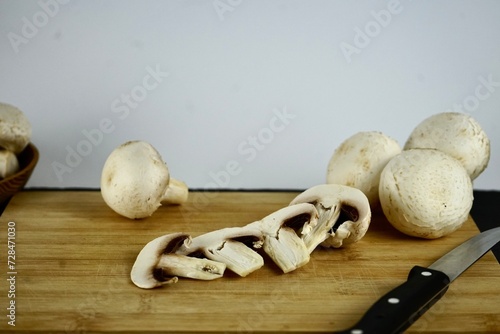 whole and folk champignons on a wooden board and a knife lies nearby
