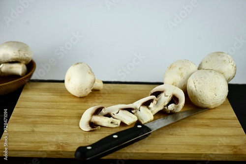 whole and folk champignons on a wooden board and a knife lies nearby