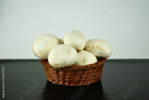 white champignons in a wicker basket on a black background