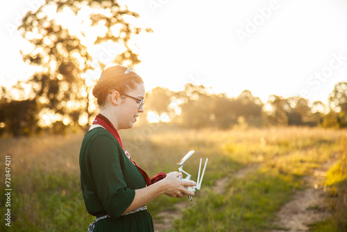 Female RPA pilot using a controller to fly a drone in rural area photo