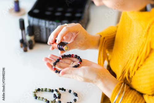 Woman putting essential oils on diffuser bracelet lava stones photo