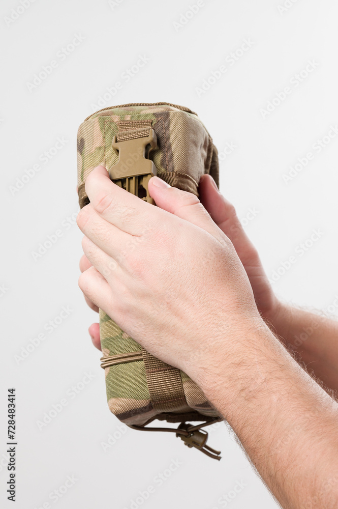 Fototapeta premium A man holds a protective cover for a monocular, pixelated fabric for the military.