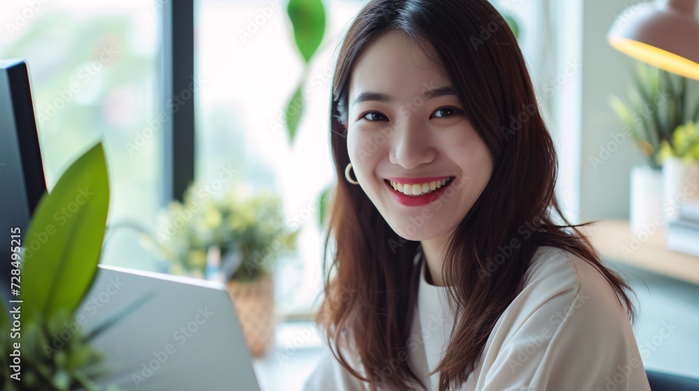 明るいオフィスで笑顔で仕事をする若い日本人ビジネスウーマン 明るいオフィスで笑顔で仕事をする若い日本人ビジネスウーマン
