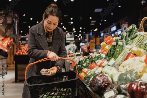 Young Woman Choosing Fresh Vegetables in Grocery Store photo