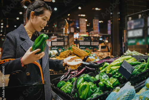 Woman Choosing Fresh Peppers at Grocery Store photo